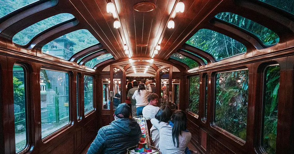 Trem Vistadome indo para Cusco com vários turistas comemorando e alguns rindo