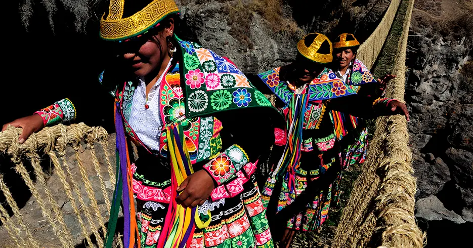 Mulheres locais atravessando a ponte Qeswachaka em trajes tradicionais