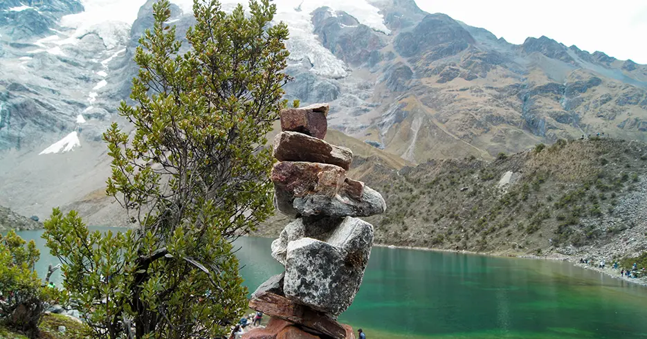 Apachetas na lagoa de Humantay e ao fundo você pode ver a lagoa turquesa Humantay e as montanhas