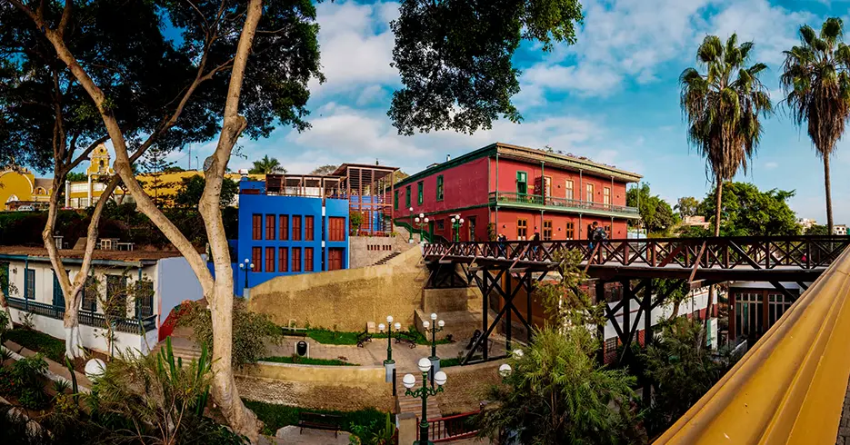 Vista do bairro do Barranco passando pela ponte dos suspiros, prédios coloridos e vegetação ao redor