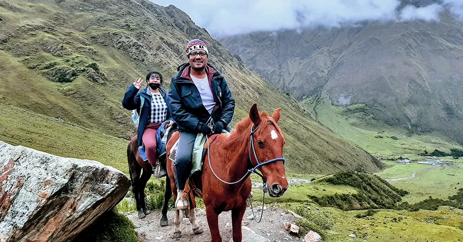 Escalada na lagoa Humantay com um cavalo e dois turistas posando para a câmera