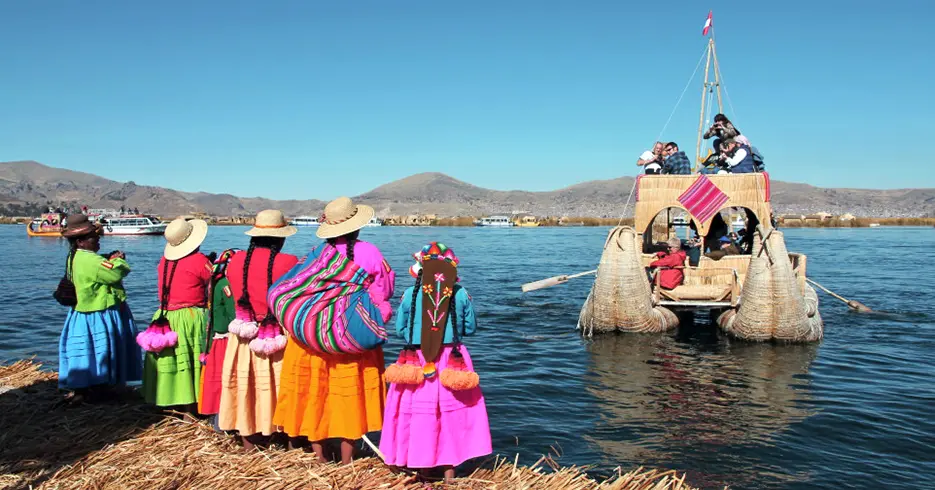 Mulheres da ilha de Uros acenando adeus aos turistas em um barco totora no Lago Titicaca em Puno