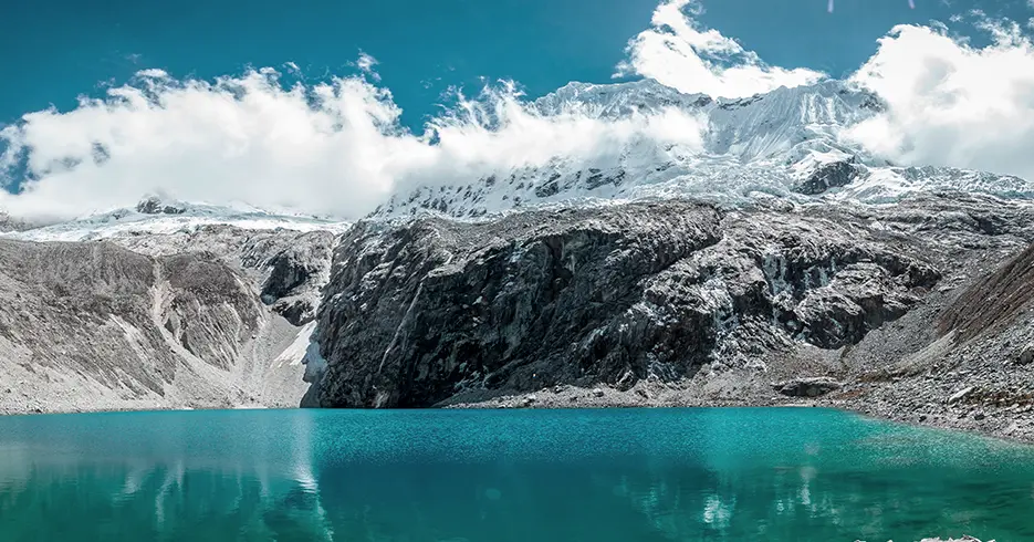 Vista da lagoa 69 com uma montanha nevada acima e a lagoa azul-turquesa e cristalina