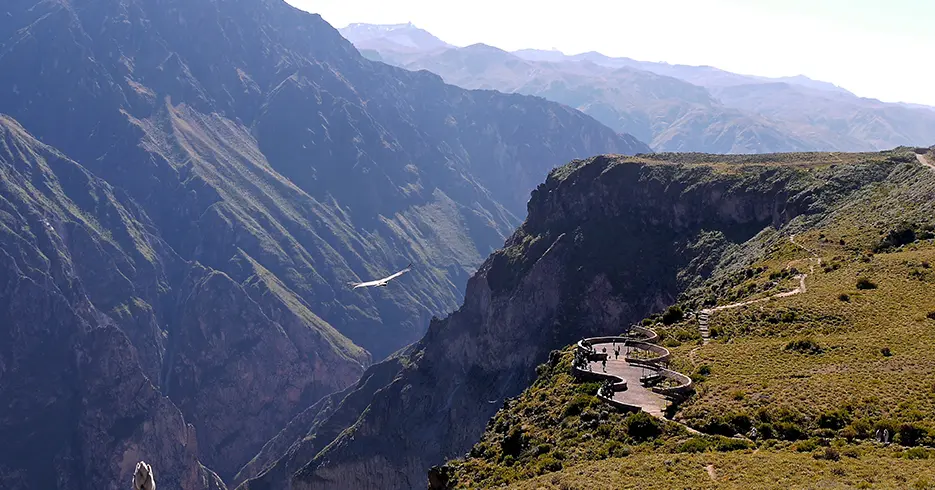 Mirante do Cânion do Colca cercado por montanhas e um condor voando