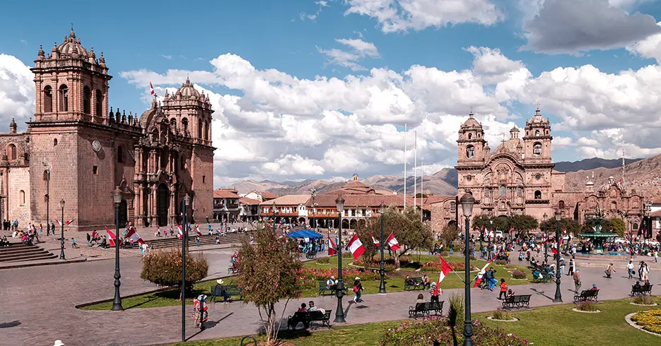 Praça principal de Cusco, com muitas bandeiras peruanas ao redor e a vista da catedral e da igreja da Companhia de Jesus
