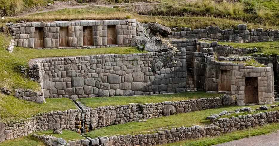 Sítio arqueológico de Tambomachay no passeio pela cidade de Cusco, cheio de construções e vegetação inca