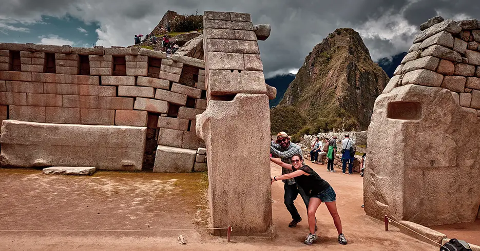Turistas posando com uma pedra em Machu Picchu,