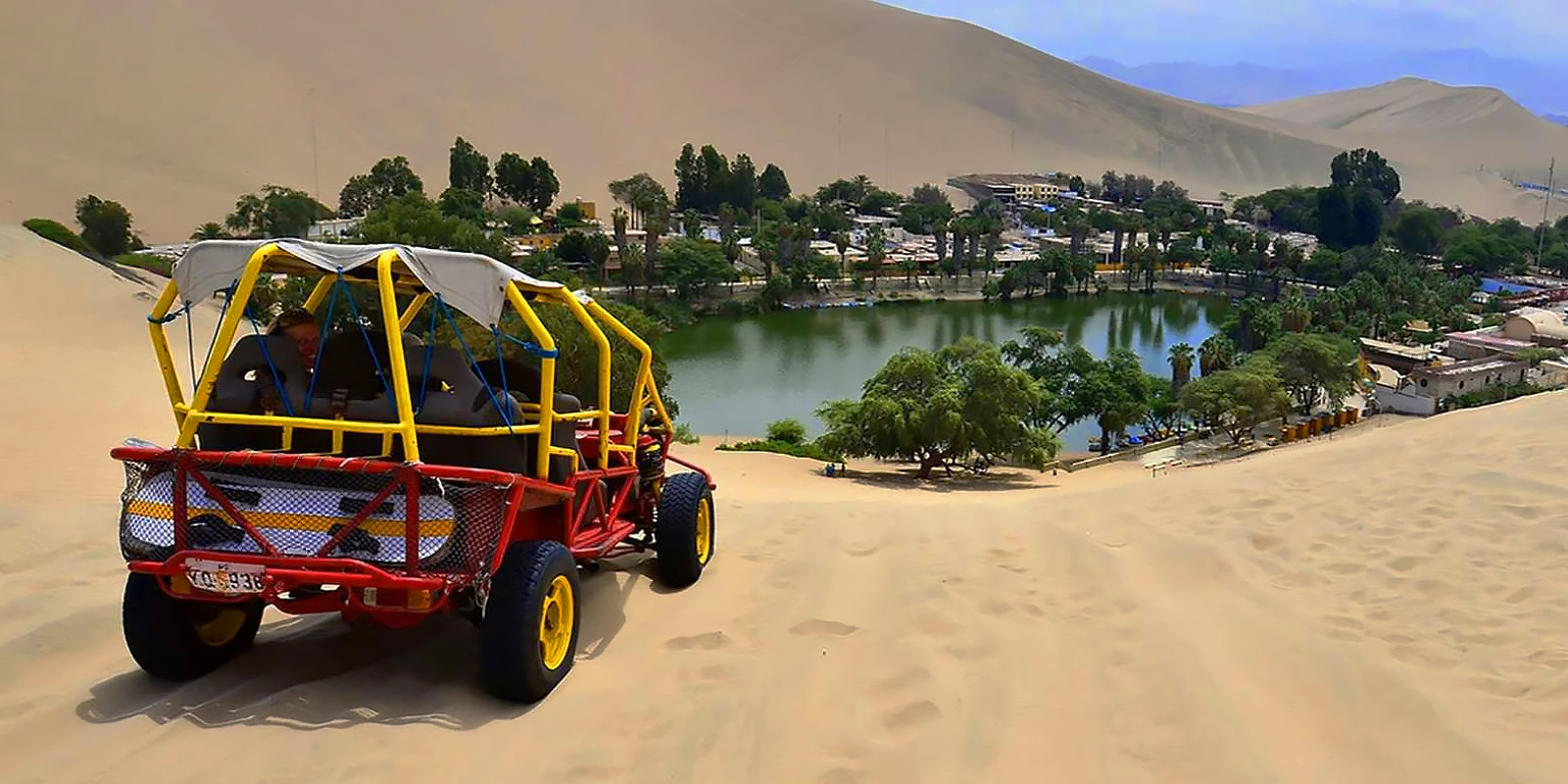 Scenic view of a red tourist vehicle driving along a coastal desert highway during the Peru Grand Travel expedition