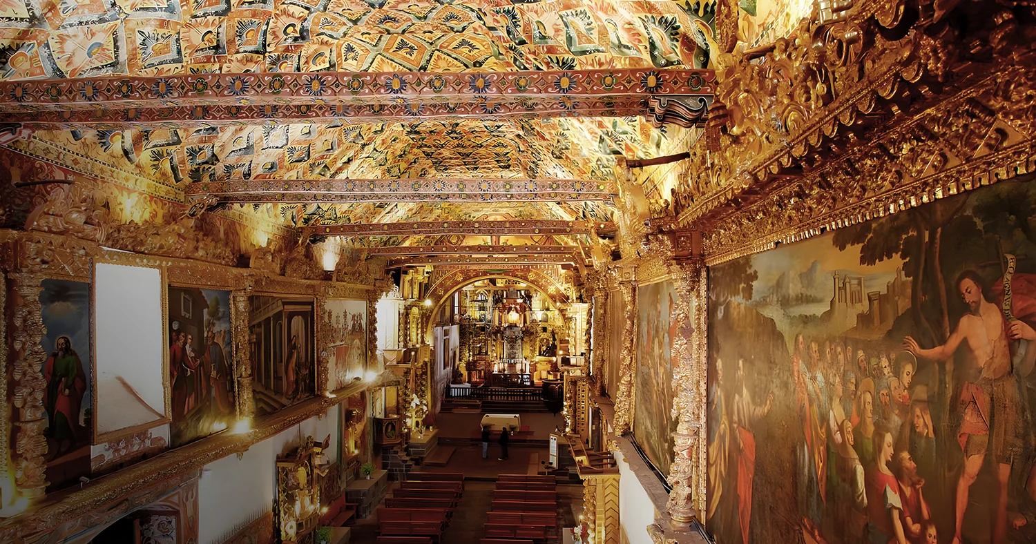 Ornate interior of Andahuaylillas Church in Cusco, Peru, featuring religious murals and a decorated ceiling