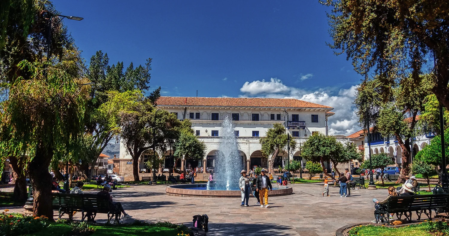 Fountain surrounded by trees, benches and colonial buildings at Plaza Regocijo in Cusco, Peru