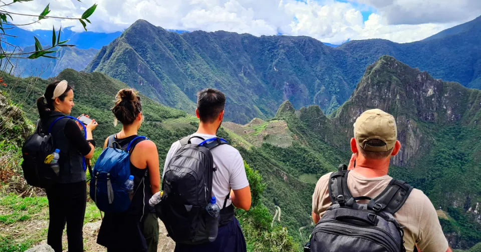 Trekkers walking along a mountain trail with local llamas on the Lares Valley Trek with Peru Grand Travel.