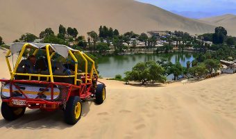 Scenic view of a red tourist vehicle driving along a coastal desert highway during the Peru Grand Travel expedition