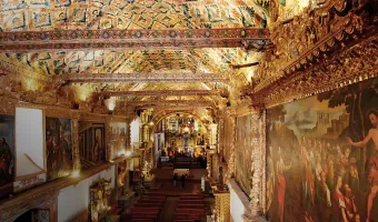 Ornate interior of Andahuaylillas Church in Cusco, Peru, featuring religious murals and a decorated ceiling