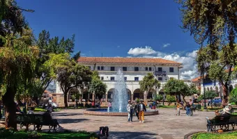 Fountain surrounded by trees, benches and colonial buildings at Plaza Regocijo in Cusco, Peru